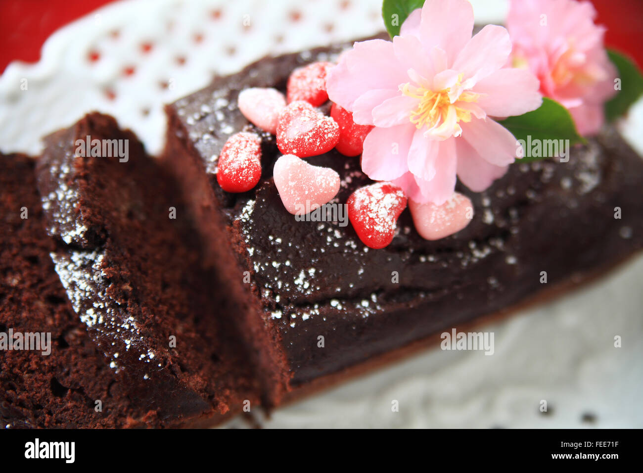 Pain au chocolat gâteau décoré avec du sucre en poudre, bonbons coeurs et des camélias Banque D'Images