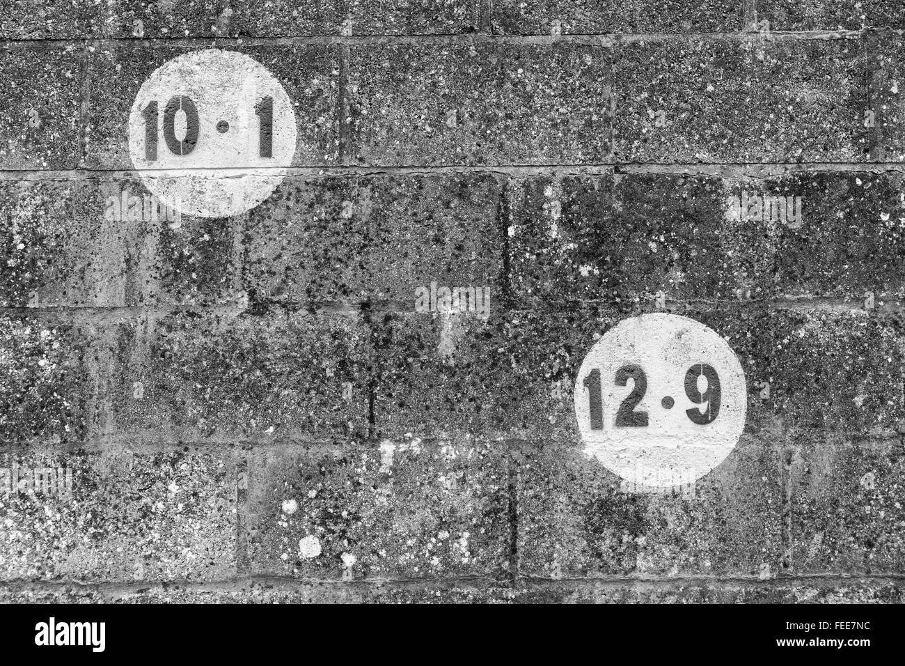 Une photo en noir et blanc de chiffres dans un cercle peint sur mur de briques sombres dans le outdoorsin l'Europe Banque D'Images