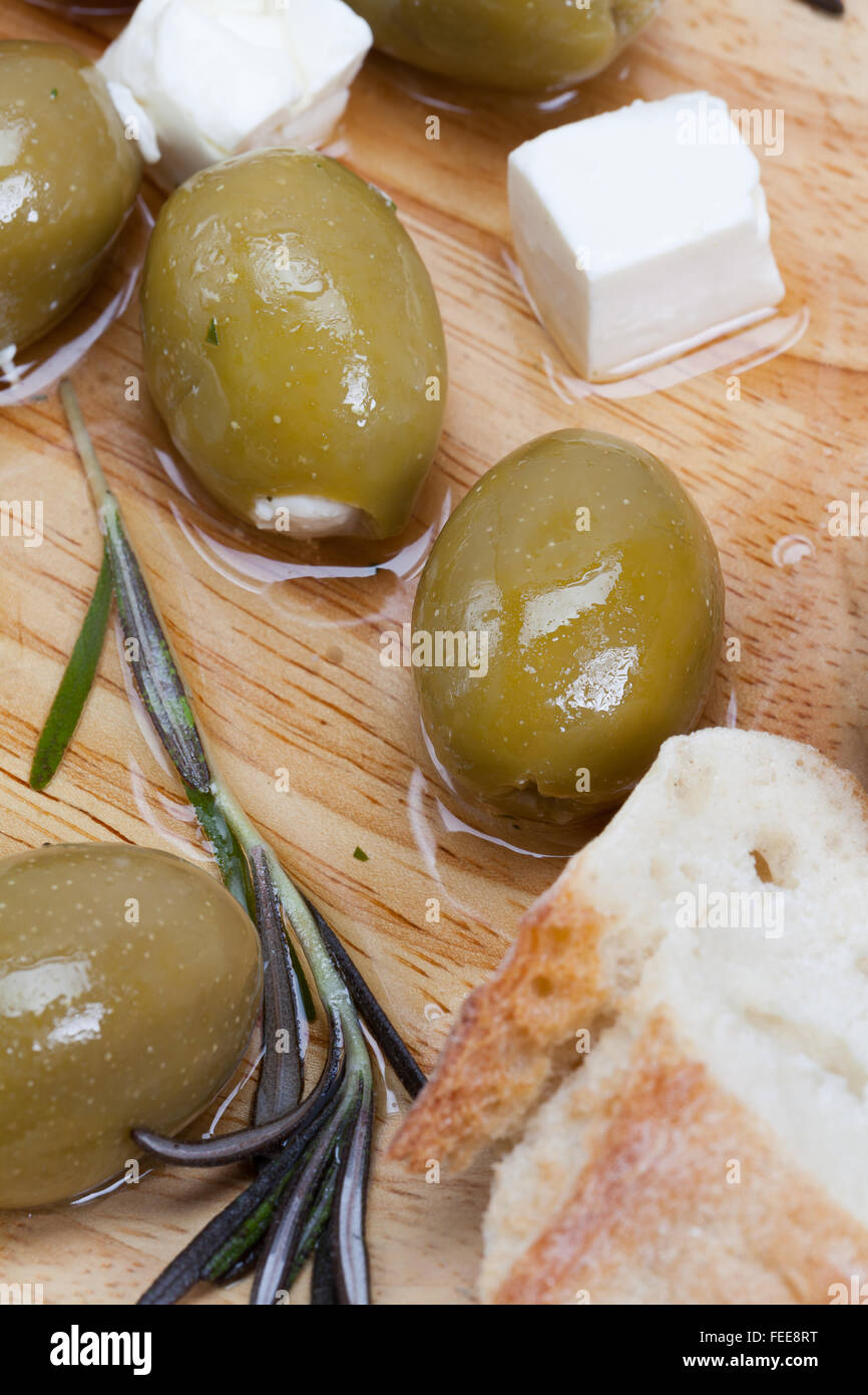 Olives vertes farcies au fromage feta sur planche de bois. Banque D'Images