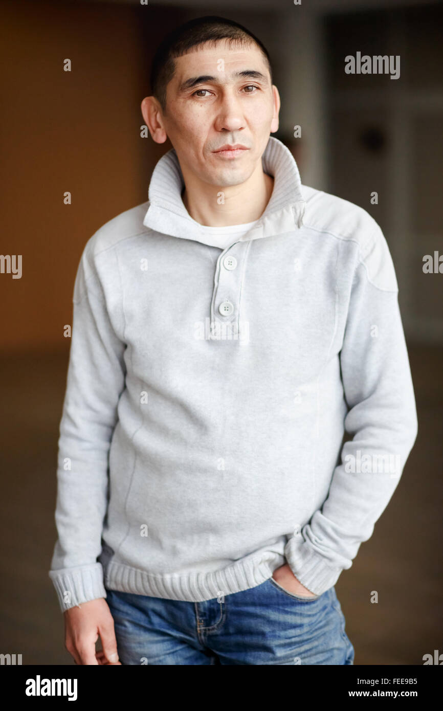 Close up portrait of man brune dans les tenues avec les cheveux courts de façon réfléchie à la recherche directement dans l'appareil photo, l'employé reçoit, habillé d'pull léger. Banque D'Images