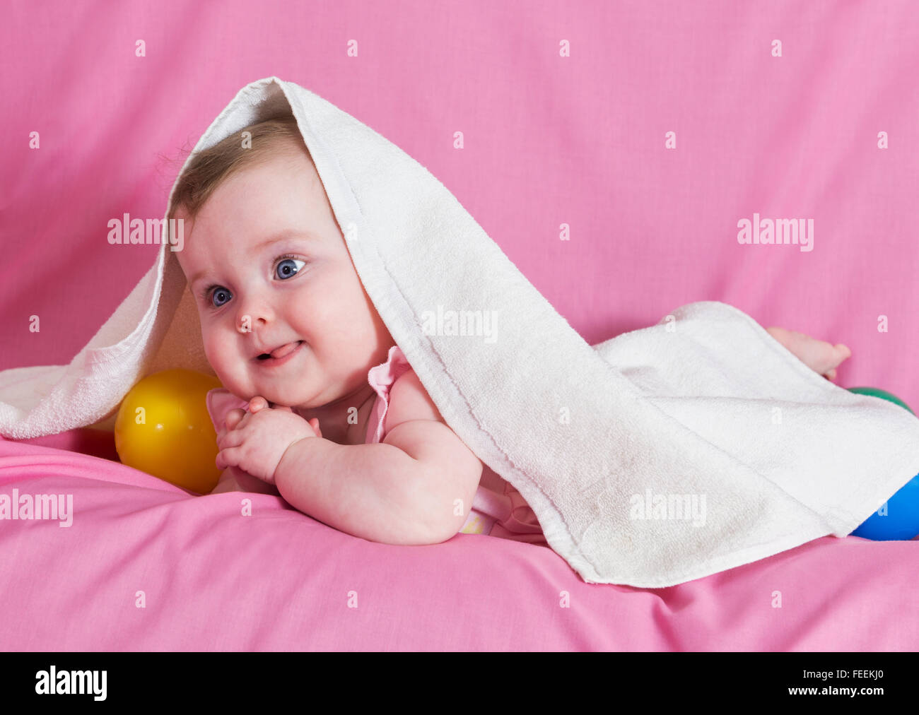 Adorable petite fille heureuse avec serviette blanche sur fond rose Banque D'Images