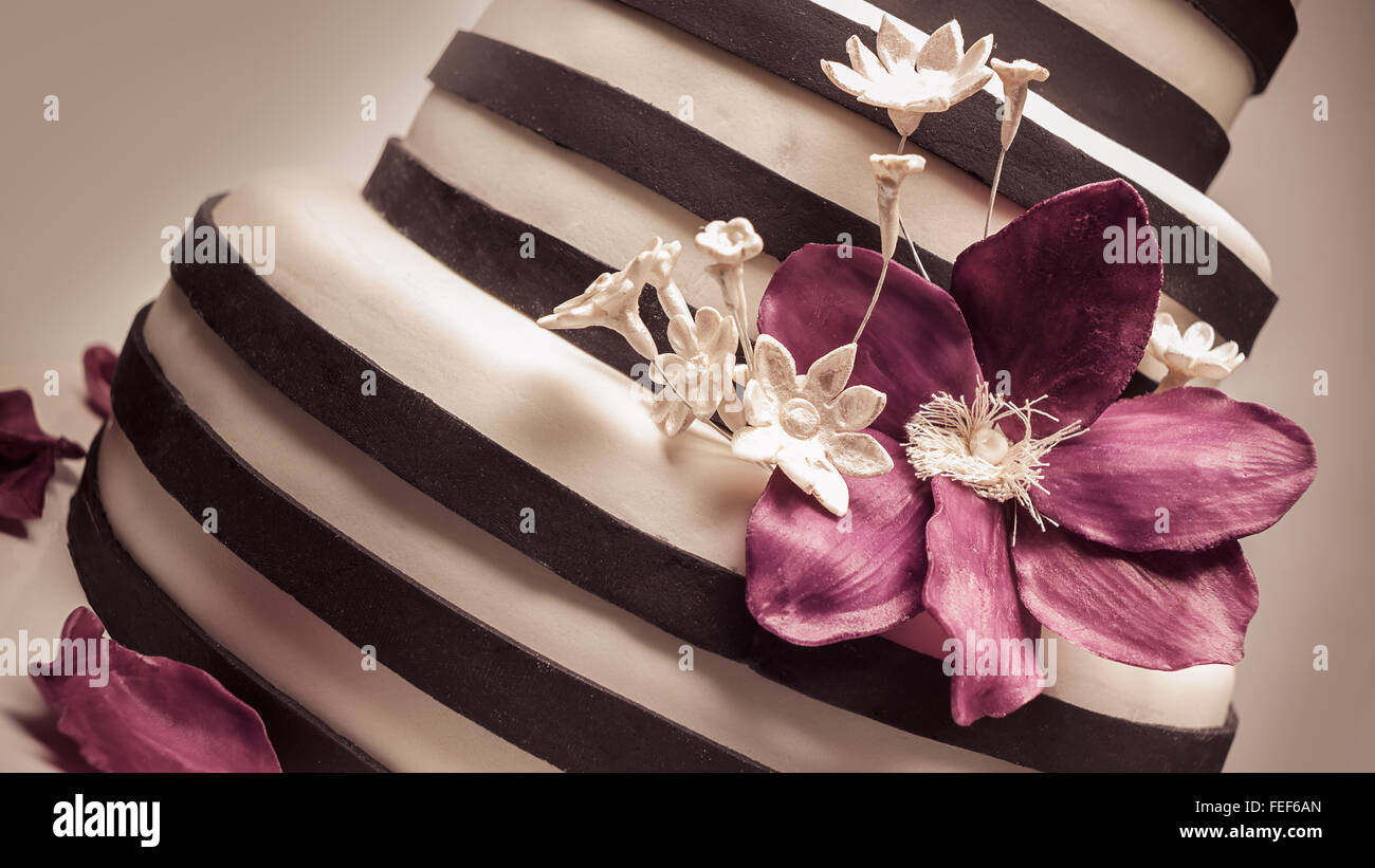 Détails d'un mariage ou d'un gâteau d'anniversaire, triple taille, en studio sur fond blanc. Purple fleurs de sucre comme décoration principale. Banque D'Images