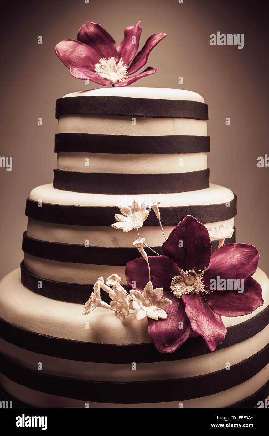 Détails d'un mariage ou d'un gâteau d'anniversaire, triple taille, en studio sur fond blanc. Purple fleurs de sucre comme décoration principale. Banque D'Images