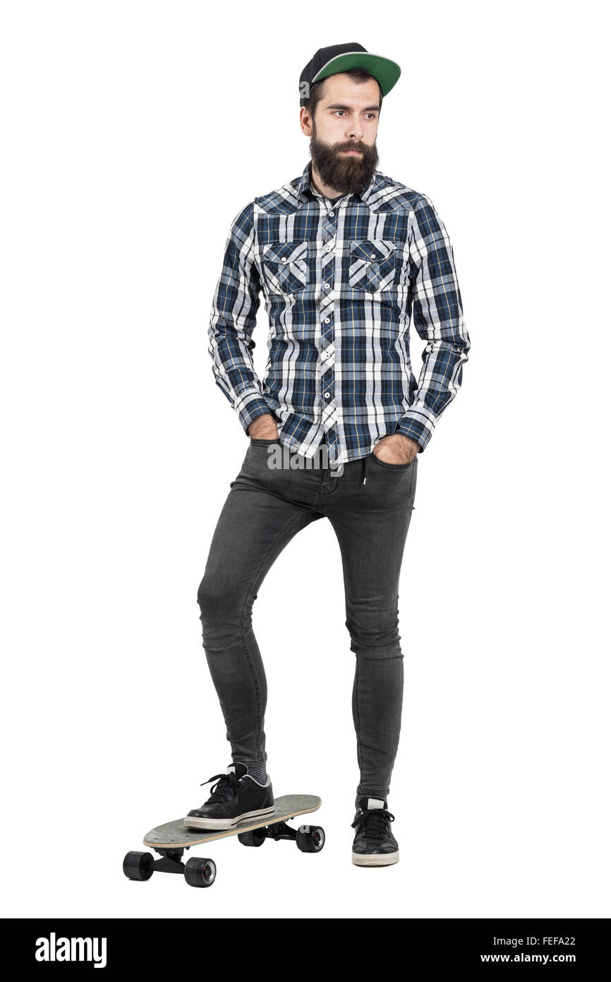 Confiant hipster barbu avec chapeau de base-ball debout sur skate board à  la recherche vers le bas. La pleine longueur du corps portrait isolated  over white Photo Stock - Alamy