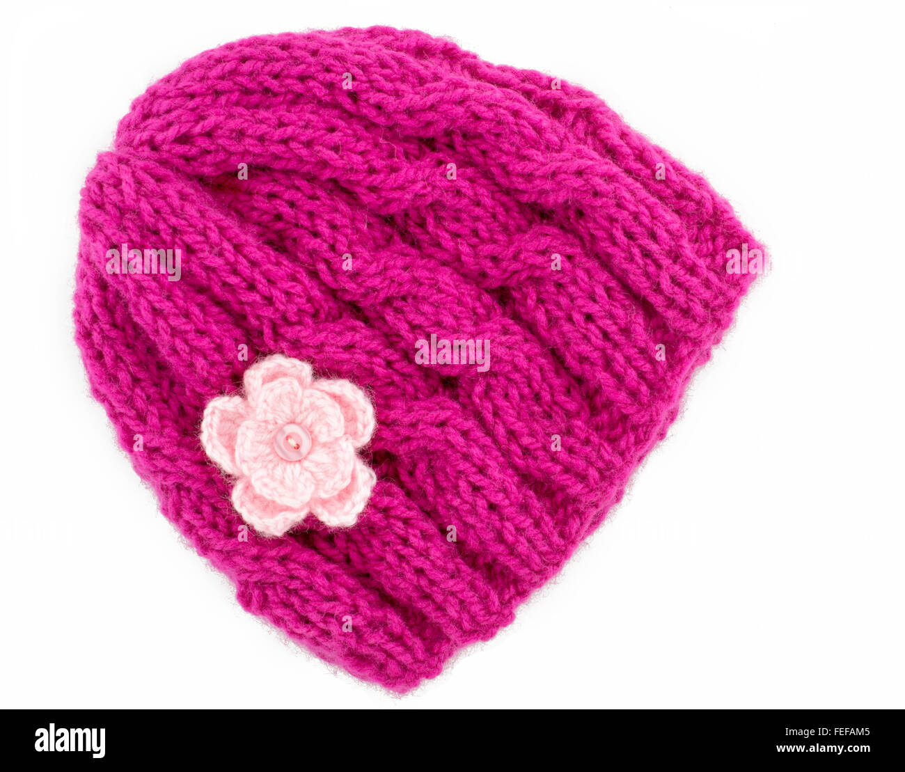 Chapeau d'hiver tricoté en laine rose avec une petite fleur au crochet, en tricot, à la main de motifs sur un fond blanc Banque D'Images