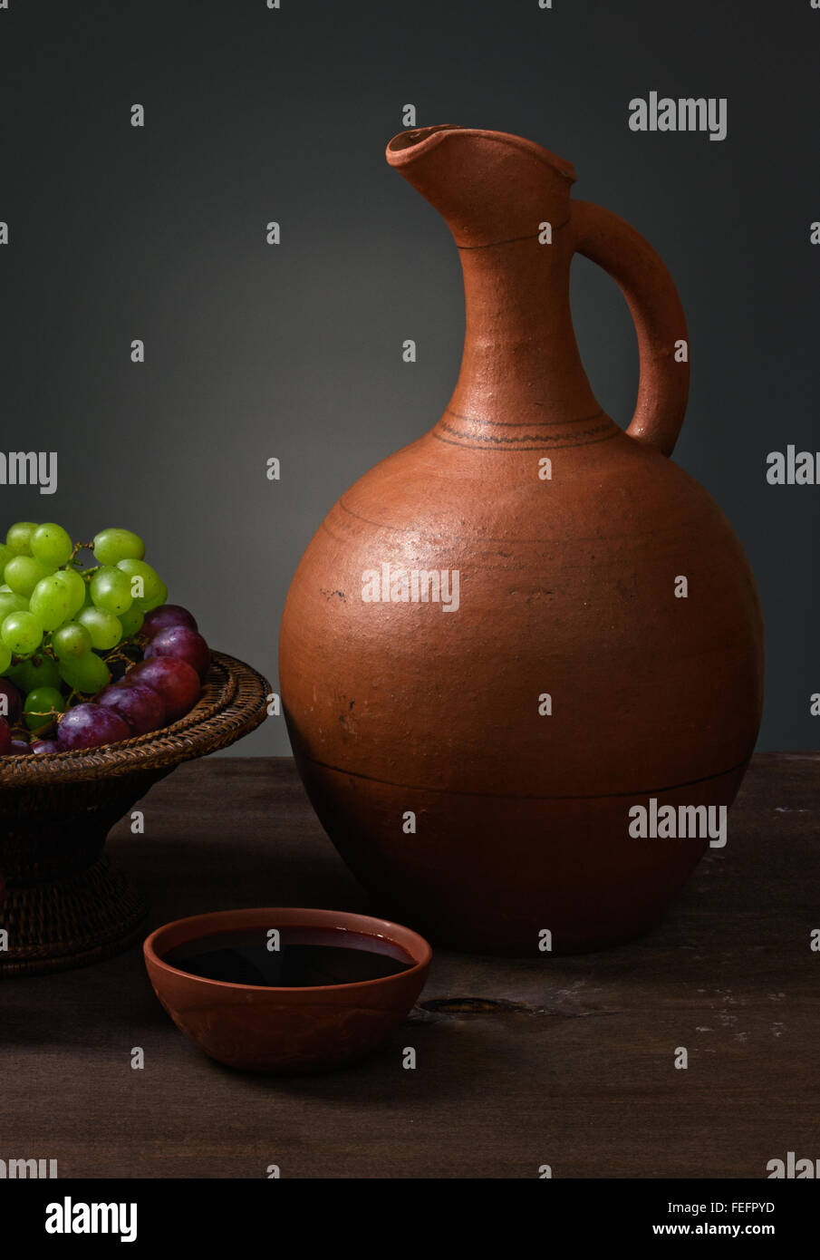 Vin rouge avec des raisins et d'une cruche sur une table en bois Banque D'Images