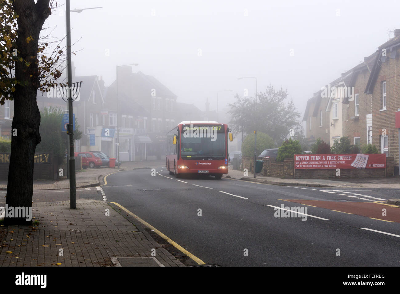 Un matin tôt London bus se déplaçant à travers les rues désertes, banlieue de brouillard. Banque D'Images