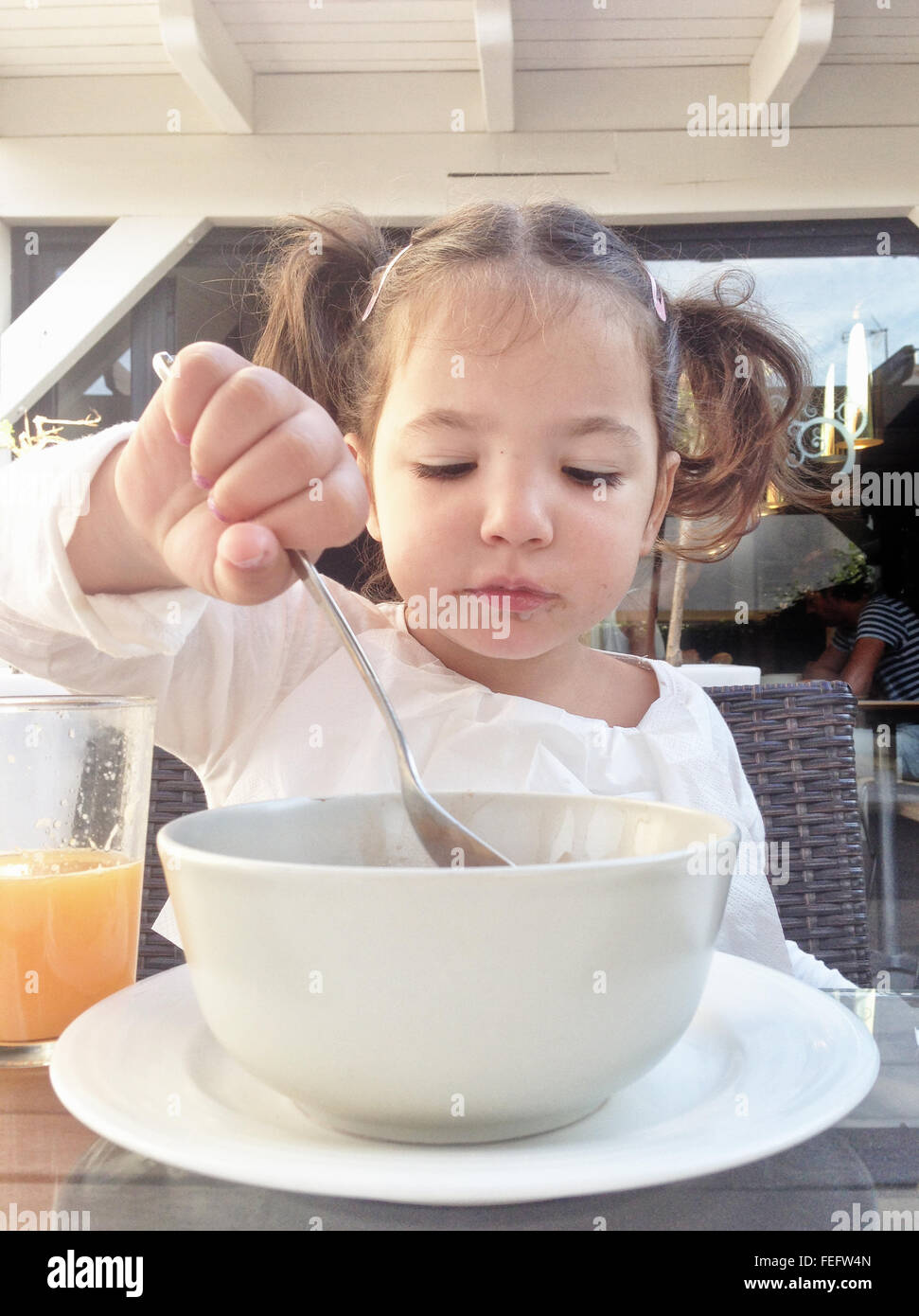 Fille enfant ayant un petit-déjeuner sain à l'extérieur. Elle est l'alimentation flocons de chocolat et jus d'orange Banque D'Images