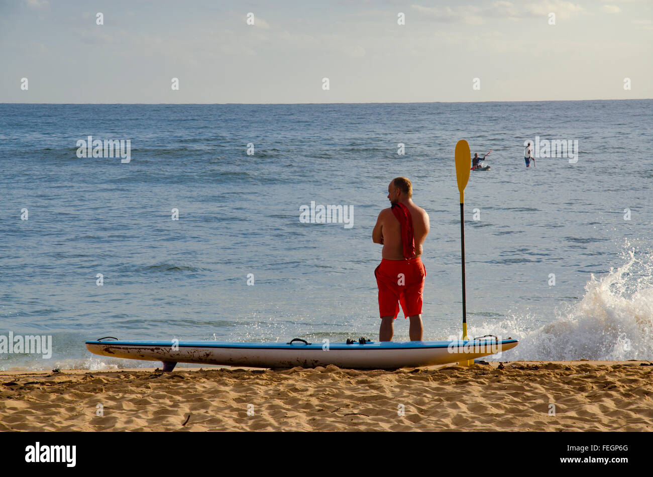 Un coureur de surf se tient à la ligne de flottaison de la plage de Collaroy à Sydney dans son short de surf qui regarde sur l'eau Banque D'Images