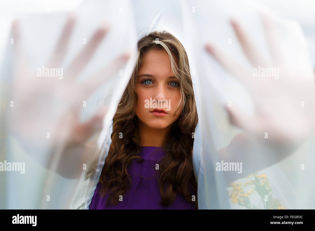 Portrait de jeune fille se cacher derrière un châle dans ses mains Banque D'Images