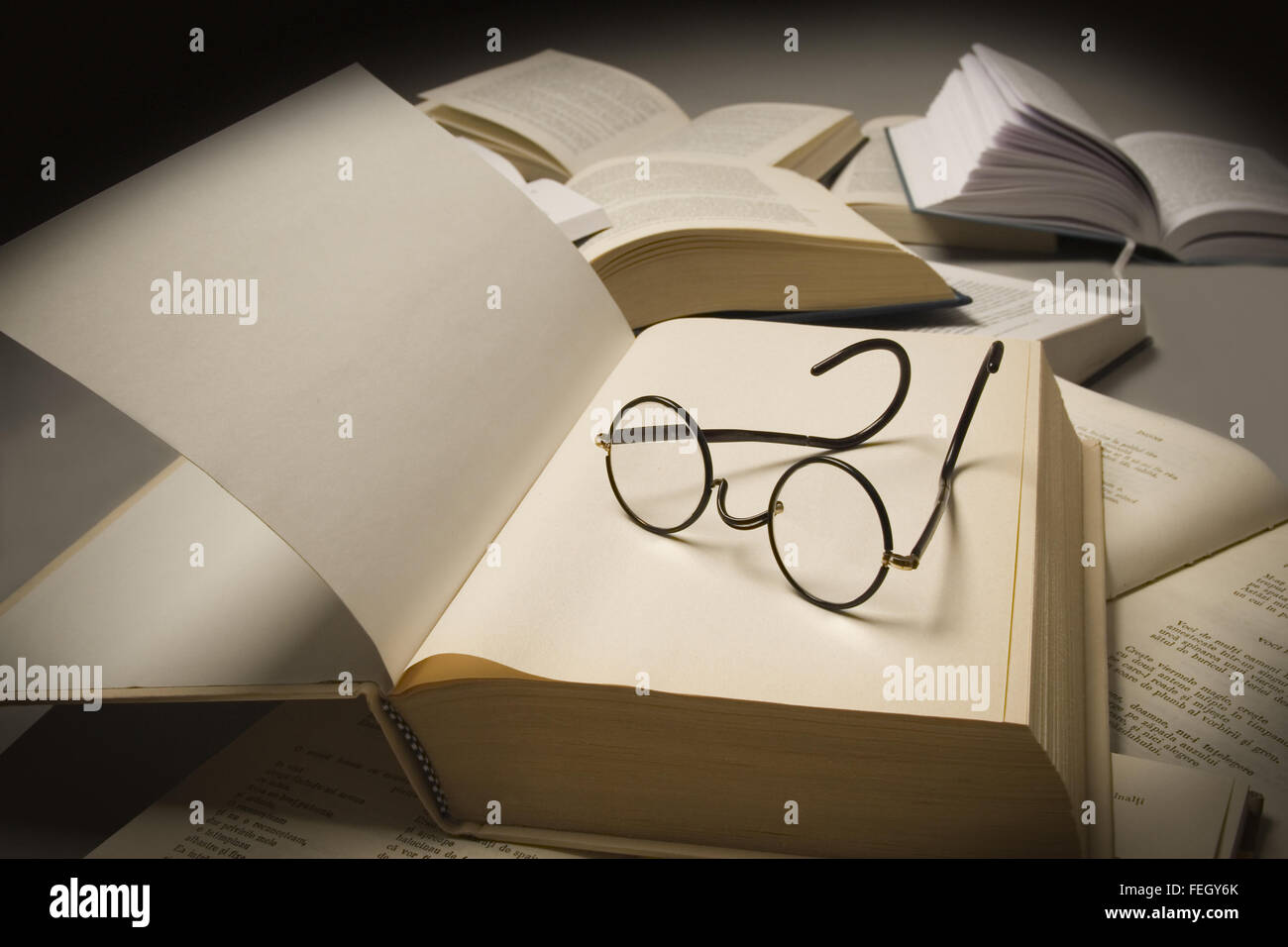 Paire de lunettes de lecture sur le dessus d'un livre ouvert, à proximité d'autres livres ouverts Banque D'Images