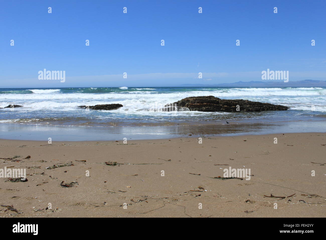 Vagues se brisant sur et à travers les rochers sur la plage de sable ...