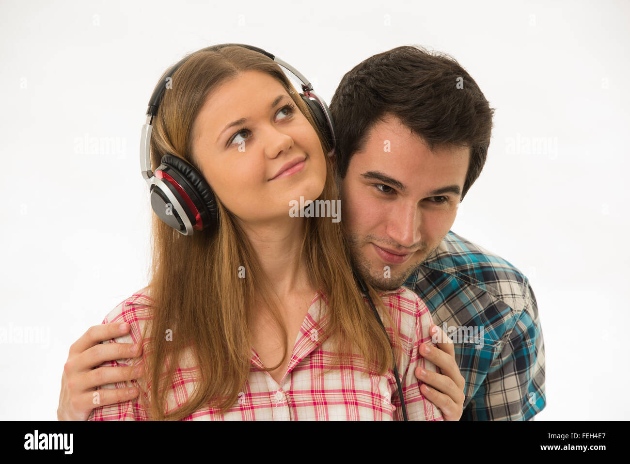 Jeune couple, homme et femme, portant vérifier shirts, woman mà avec des écouteurs Banque D'Images