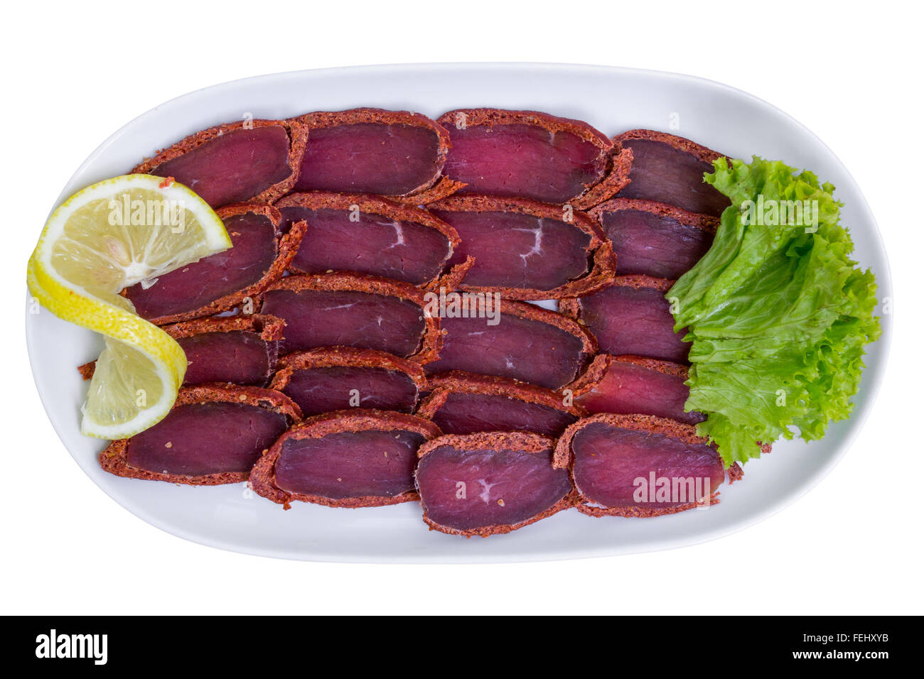 Basturma, le porc de la viande séchée avec du citron sur plaque blanche, vue du dessus, isolé Banque D'Images