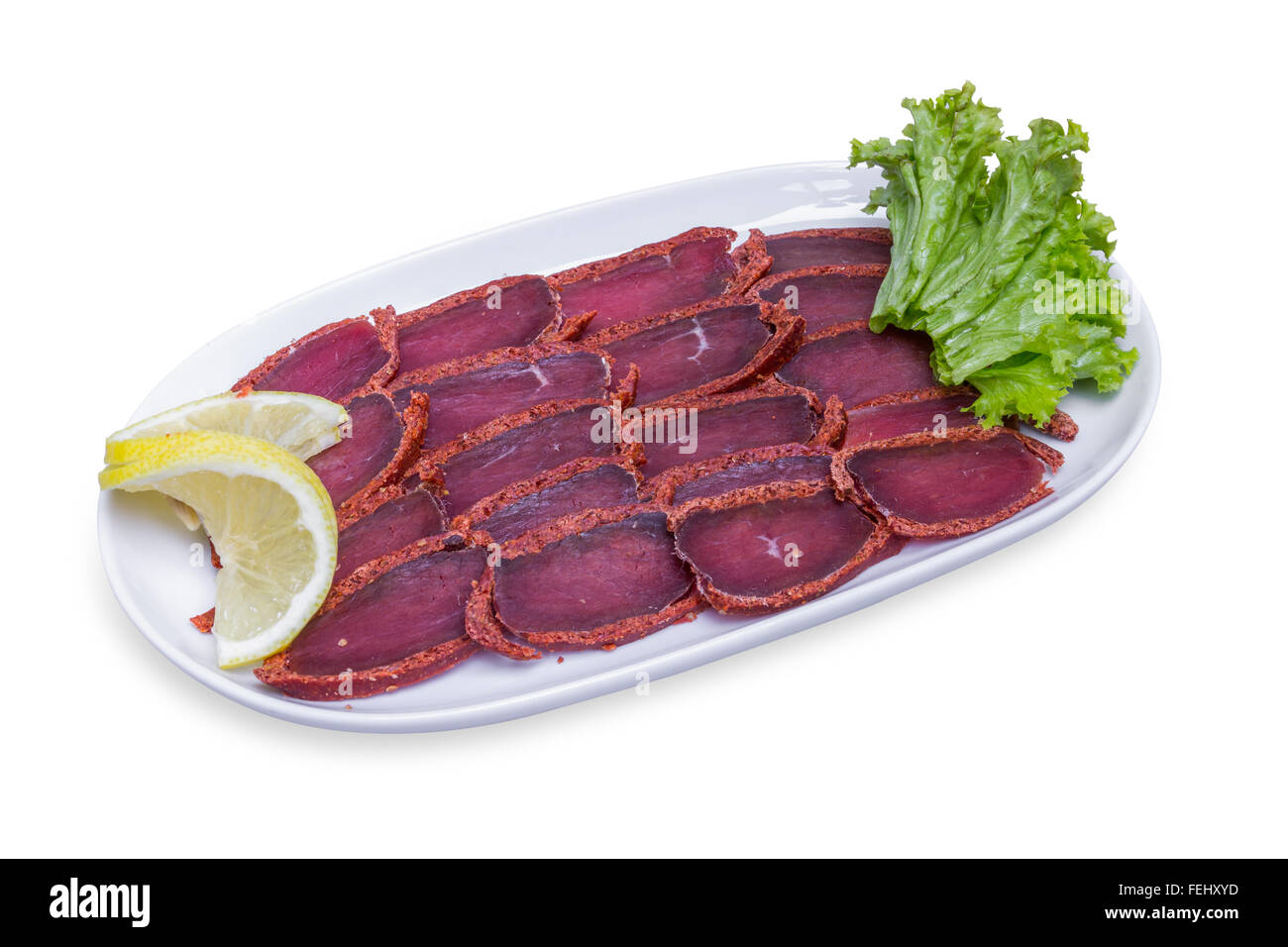 Basturma, le porc de la viande séchée avec du citron sur plaque blanche, isolée avec clipping path Banque D'Images