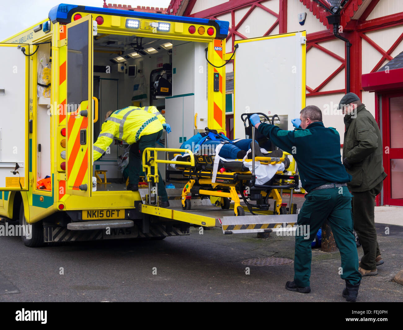 Les ambulanciers le chargement d'une victime sur un chariot d'urgence en ambulance NHS Banque D'Images
