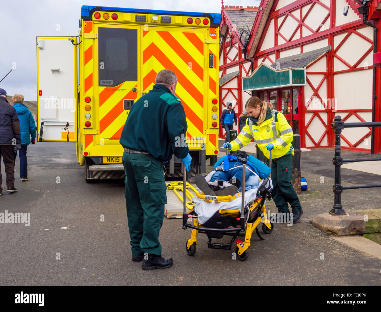 Les ambulanciers le chargement d'une victime sur un chariot d'urgence en ambulance NHS Banque D'Images