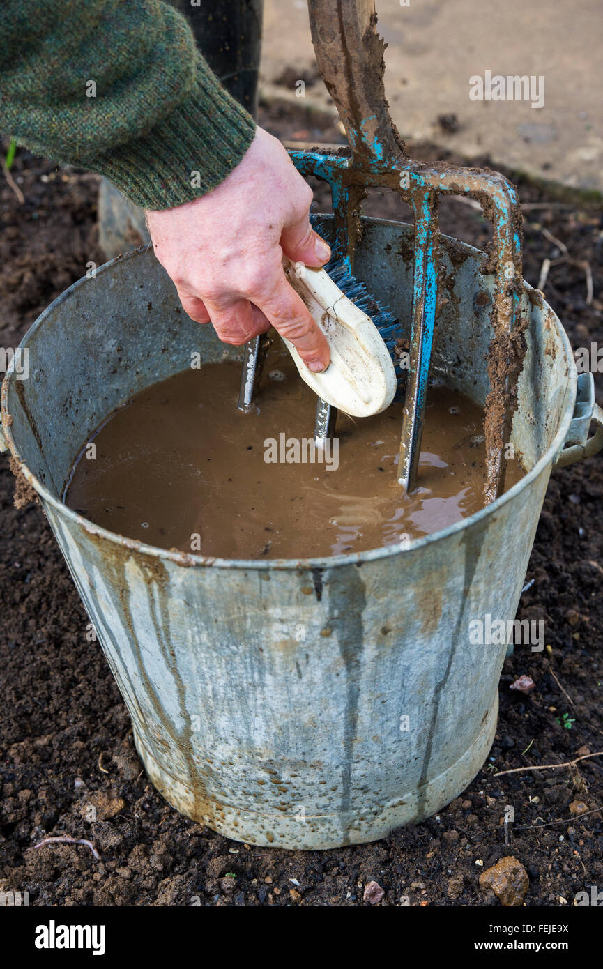 Gardner avec un seau d'eau des sols Nettoyage d'une fourche de jardin Banque D'Images