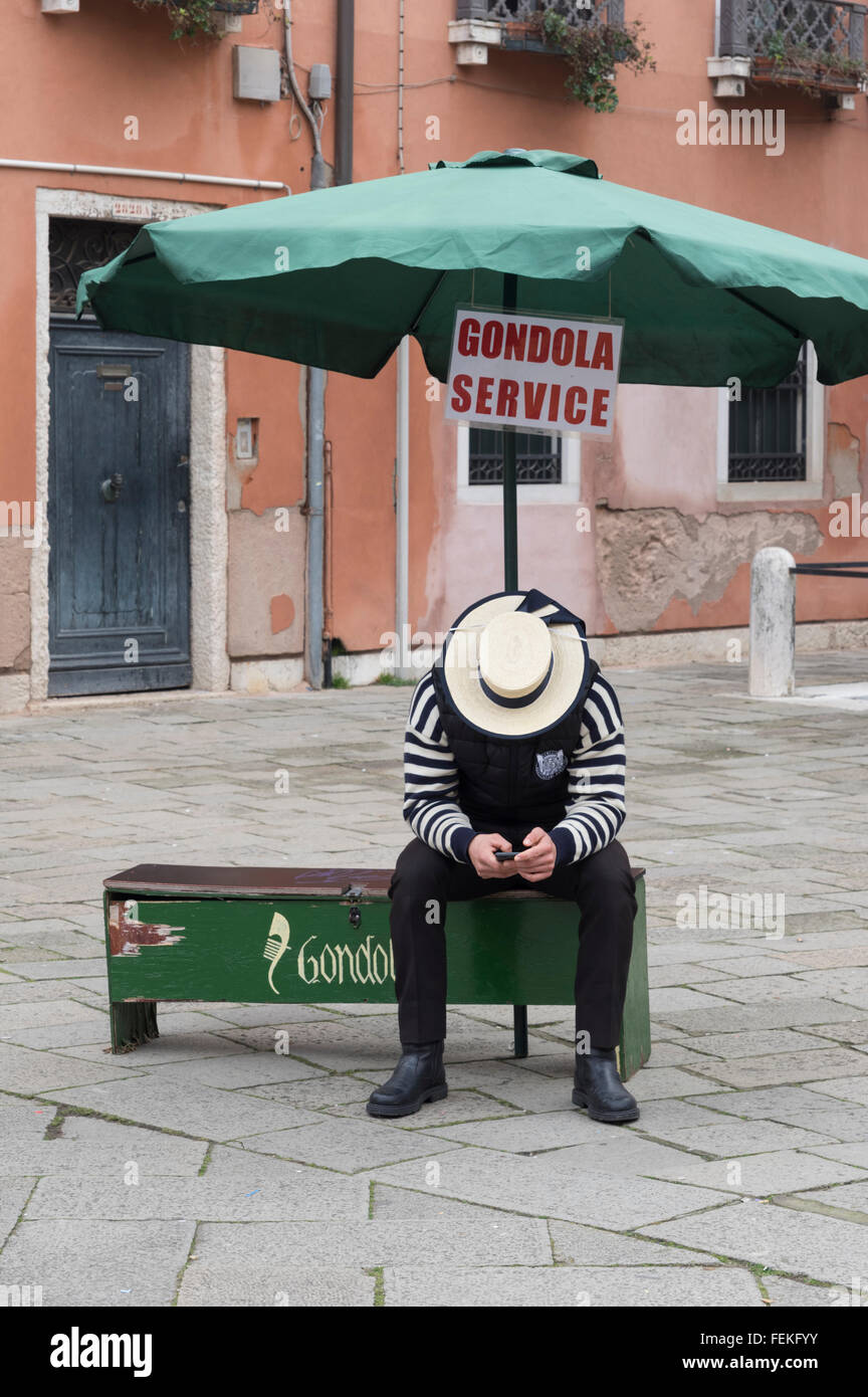 Un gondolier vérifie son téléphone cellulaire dans l'attente d'un client dans la semaine du Carnaval Venise 2016 Banque D'Images