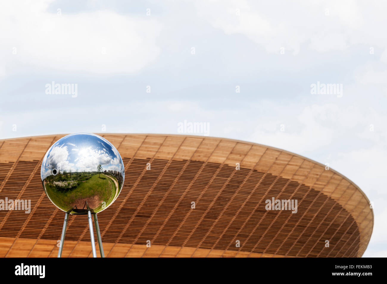 Une sphère réfléchissante sculpture avec le vélodrome en arrière-plan, le Parc Olympique, Stratford, London, E15. Banque D'Images