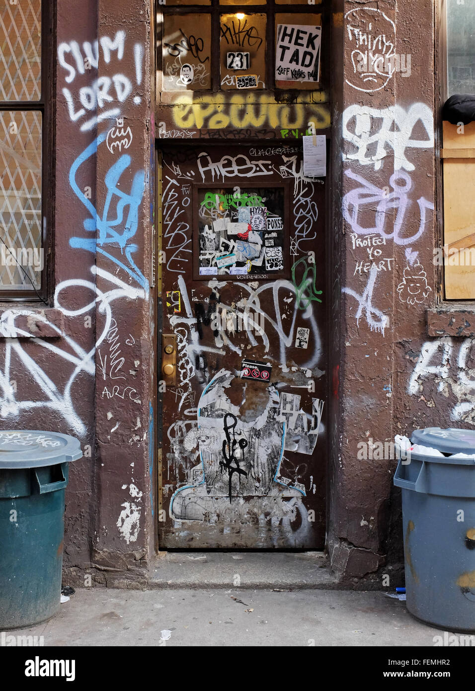 Entrée d'un bâtiment délabré sur East Fourth Street à Greenwich Village avec des poubelles et des graffitis. New York City Banque D'Images