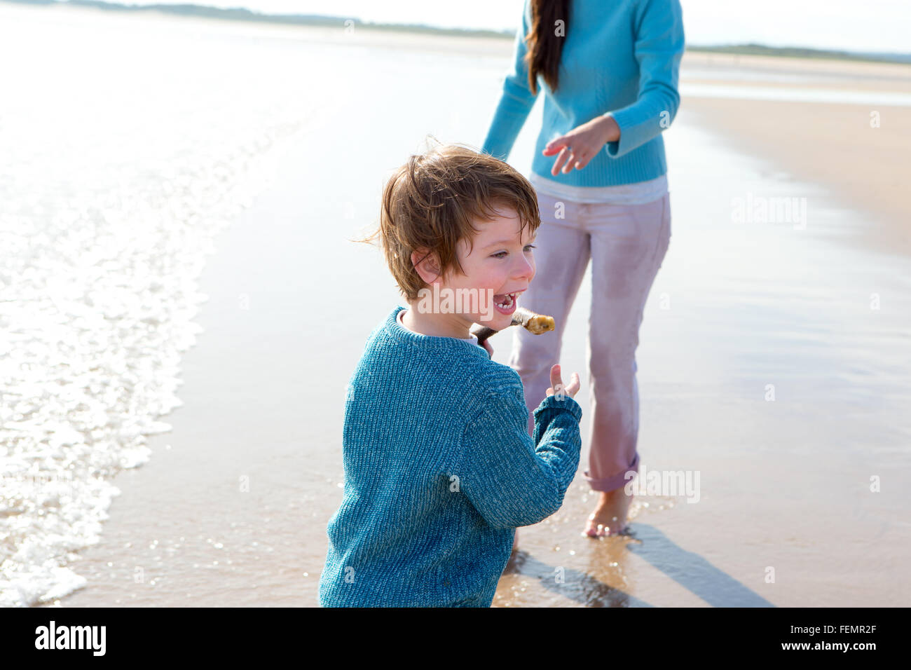Petit Garçon jouant sur la plage avec sa mère. Banque D'Images