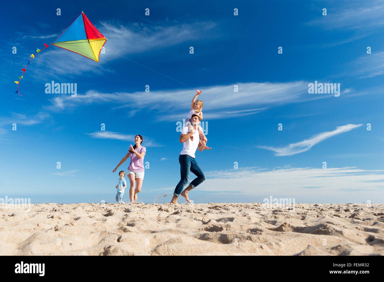 Famille de quatre flying a kite sur la plage. Banque D'Images