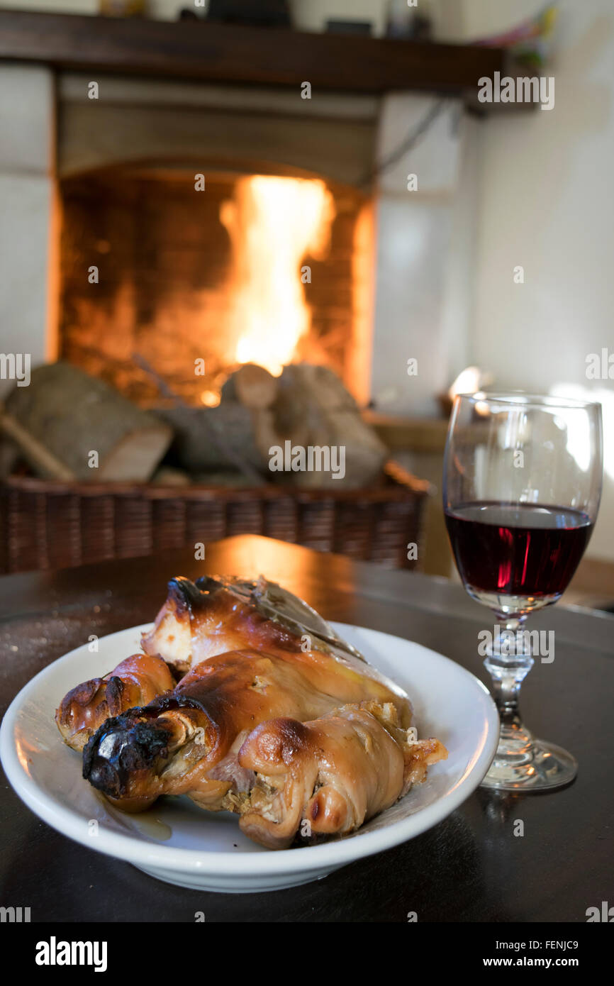 Gobelet de vin rouge et faites rôtir le porcelet de manger autour de la cheminée Banque D'Images