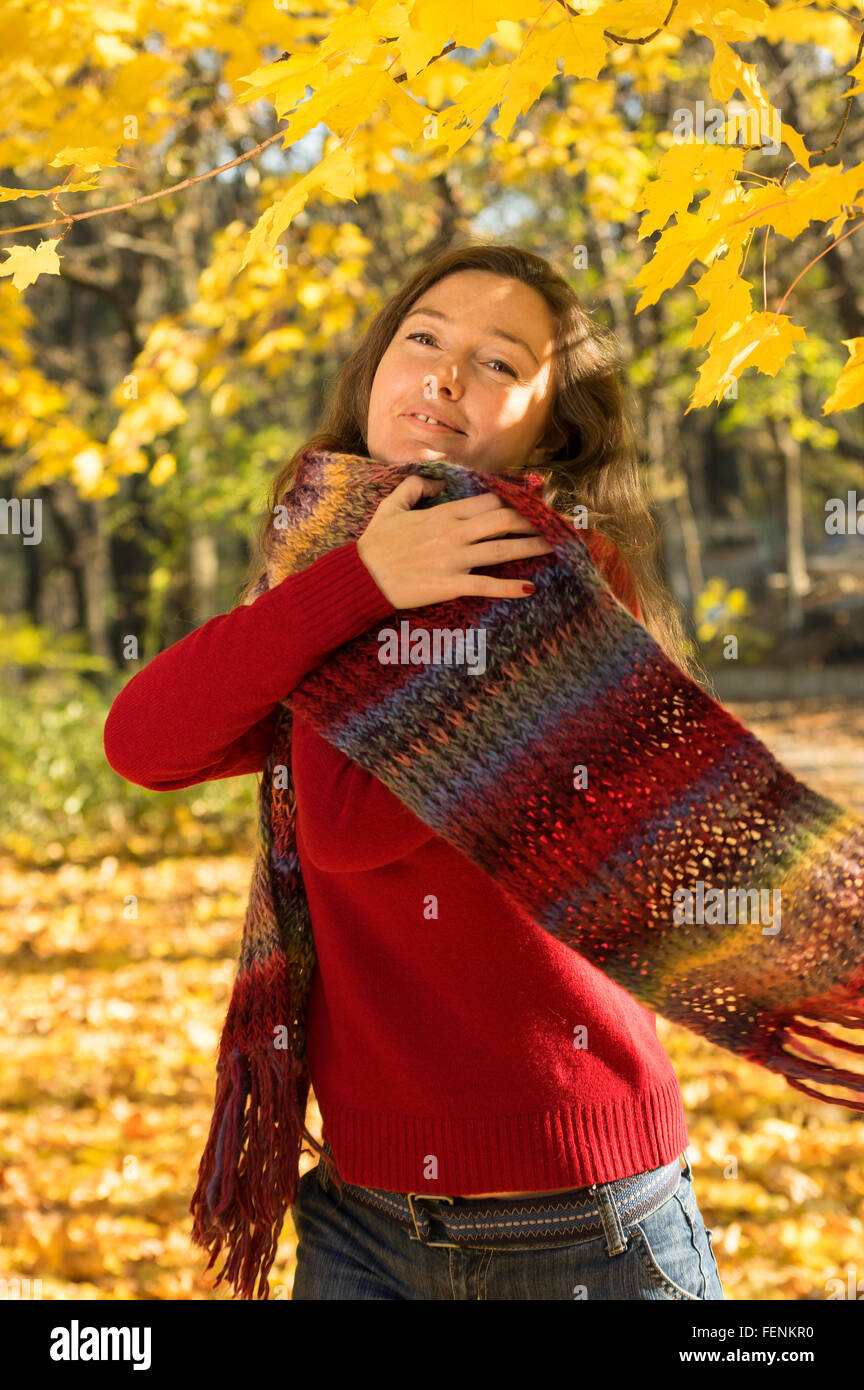 Femme avec les cheveux bruns en forêt d'automne. Accolade avec un foulard multicolore Banque D'Images