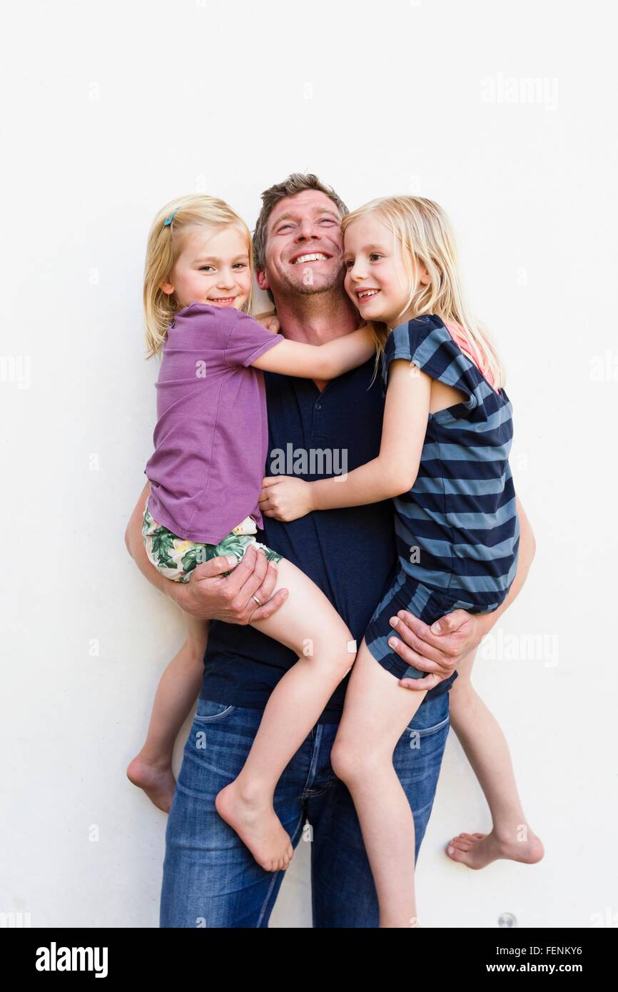 Portrait of mature man deux jeunes filles en face de mur blanc Banque D'Images