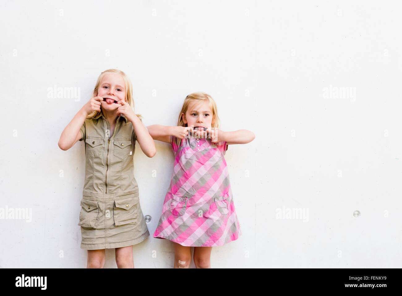 Portrait de deux sœurs mignon pulling faces en face du mur blanc Banque D'Images