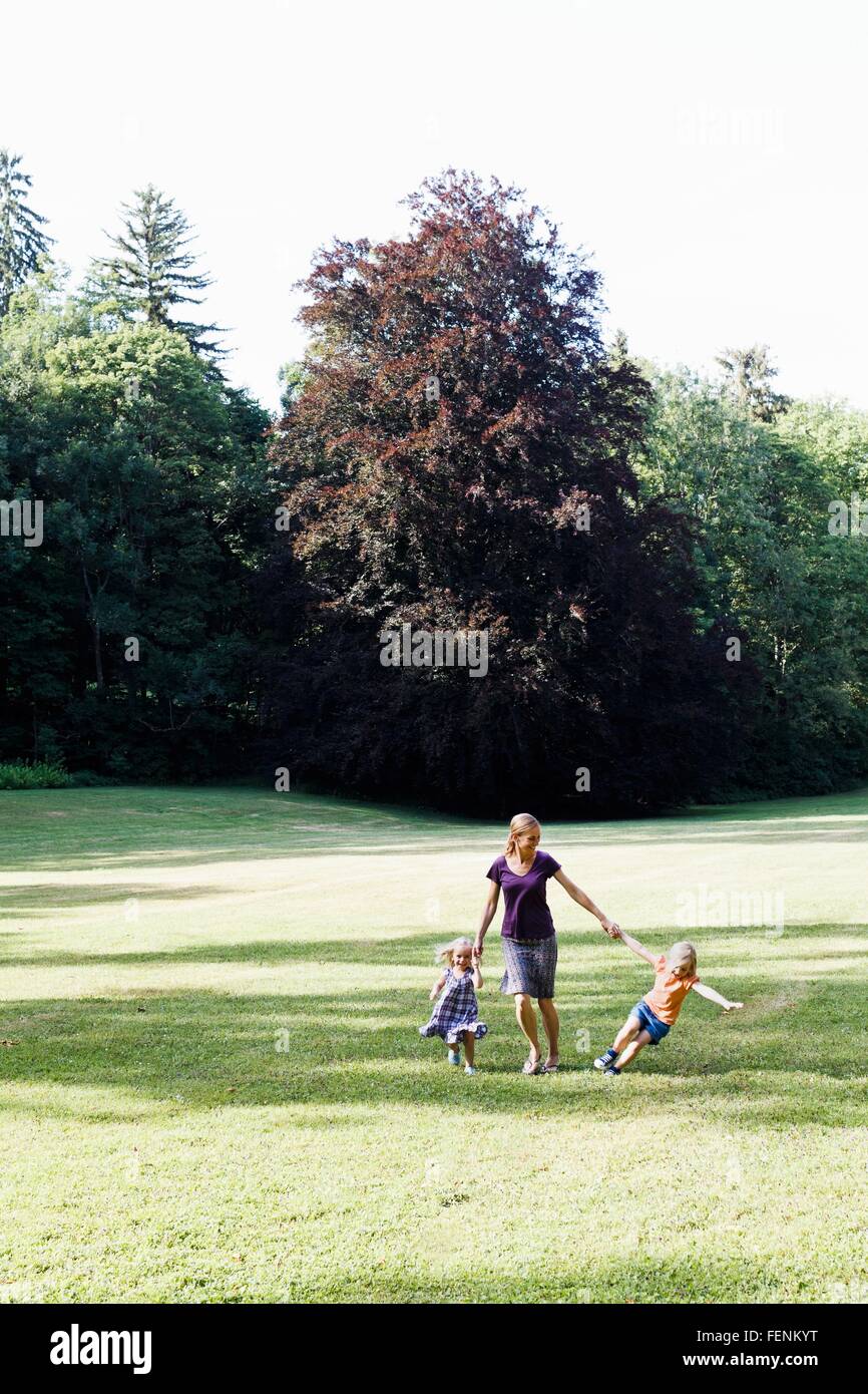 Mid adult woman et deux filles se tenant la main et running in park Banque D'Images