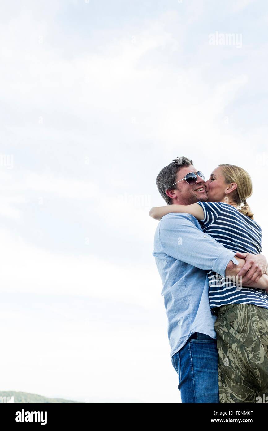 Low angle view of romantic couple hugging and kissing against sky Banque D'Images