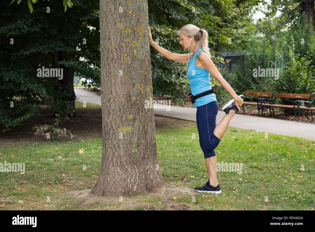 Mature Woman stretching leg alors que la formation dans park Banque D'Images