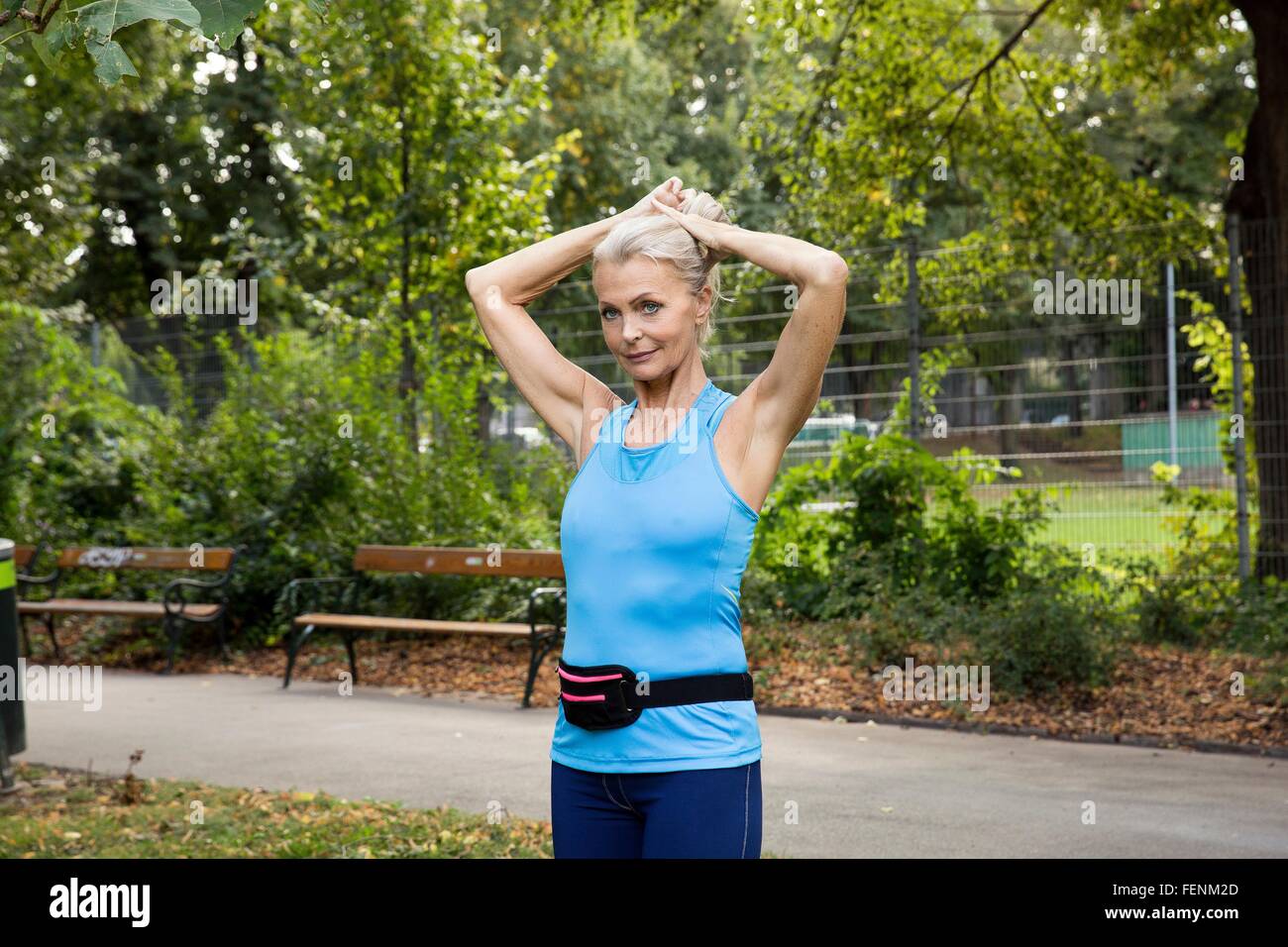 Femme mature d'attacher les cheveux alors que la formation dans park Banque D'Images