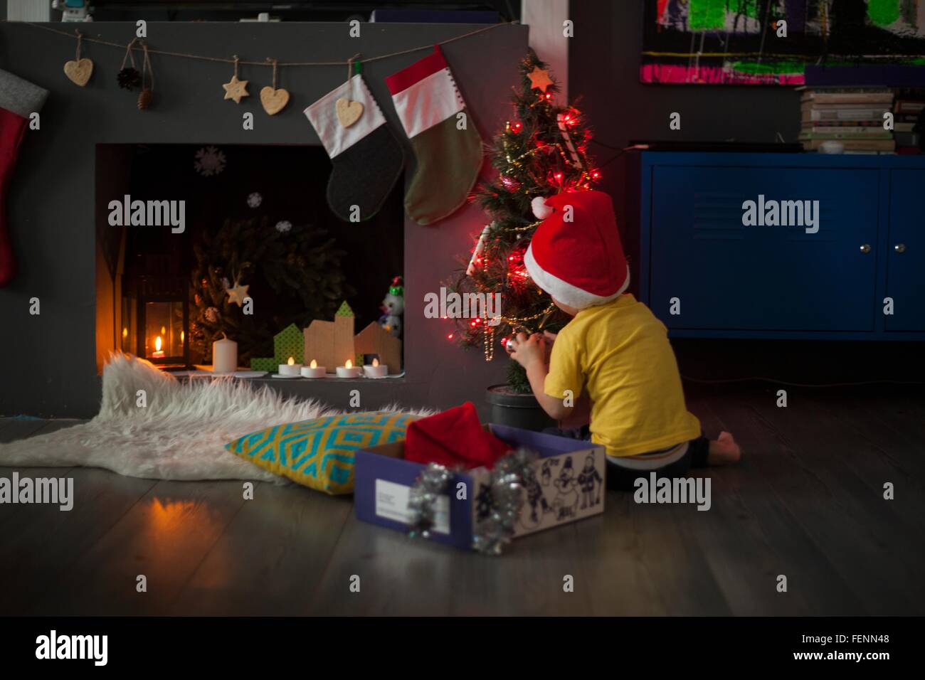 Tout-petits mâles de la préparation de l'arbre de Noël devant le foyer Banque D'Images