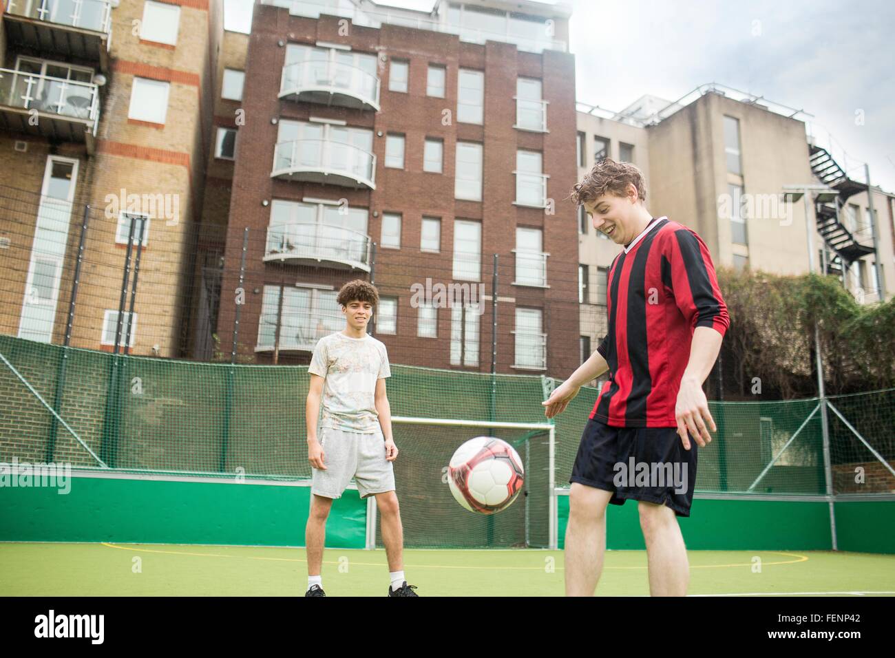 Deux jeunes hommes jouent au football sur un terrain de football urbain Banque D'Images