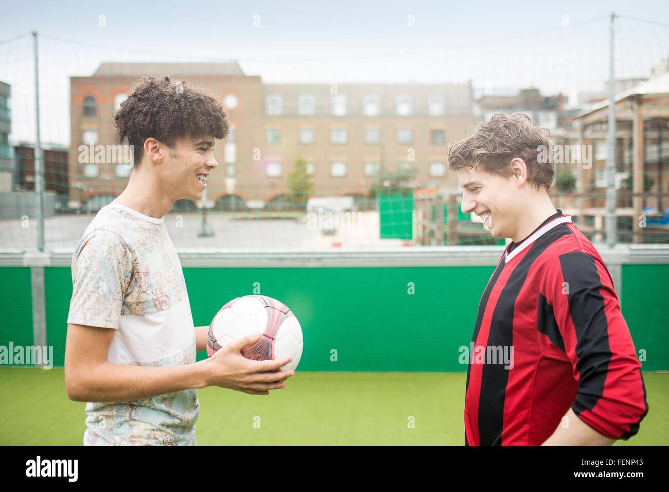 Deux jeunes hommes jouent au football sur un terrain de football urbain Banque D'Images