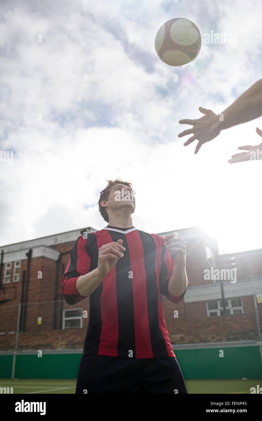 Deux jeunes hommes jouant au football sur un terrain de football urbain Banque D'Images