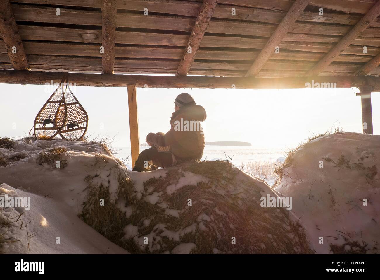 Man sitting on snowy botte en grange avec raquettes, Oural, Russie Banque D'Images