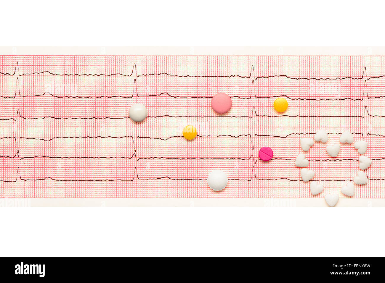 Coeur en forme de coeur blanc comprimés et blanc, jaune et comprimés roses sur papier les résultats de l'ECG isolé sur fond blanc Banque D'Images