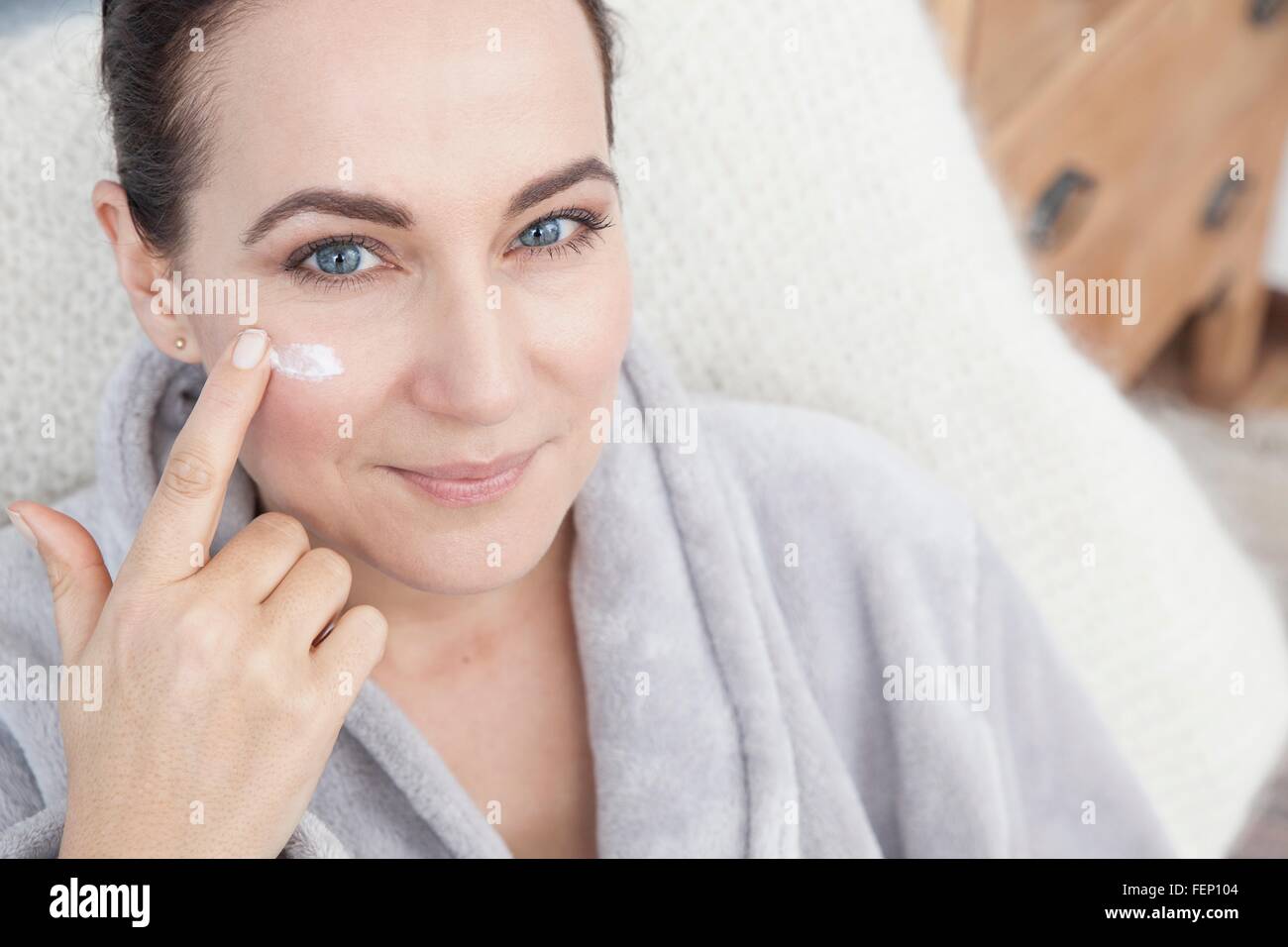 Young woman applying moisturizer à face Banque D'Images