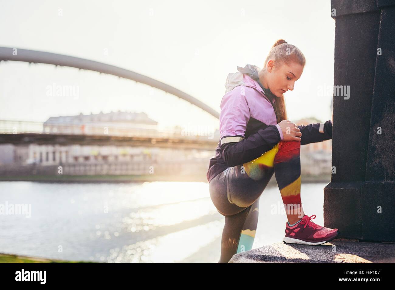 Mid adult female runner réchauffe au city riverside Banque D'Images