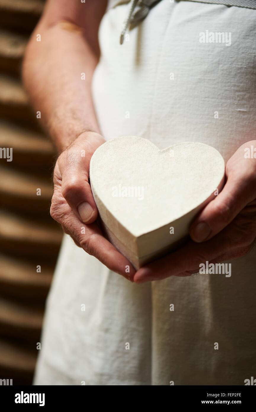 Portrait de personne portant un tablier holding heart shaped gift box Banque D'Images