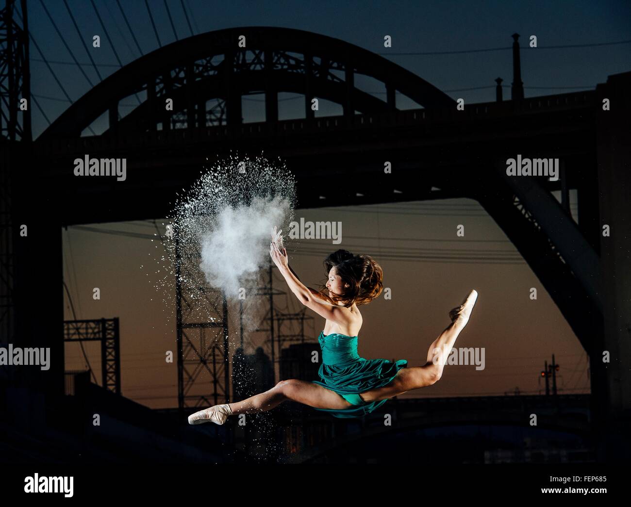 Jeune danseuse en sautant tout en relâchant l'explosion de poudre au coucher du soleil, Los Angeles, USA Banque D'Images