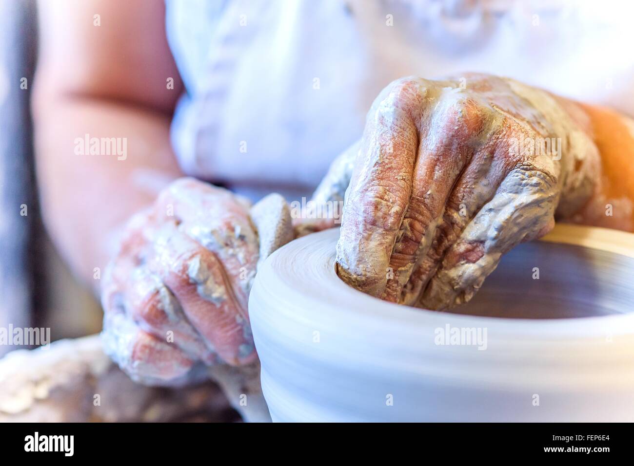 Près des mains de potter femelle faisant pot sur potters wheel Banque D'Images