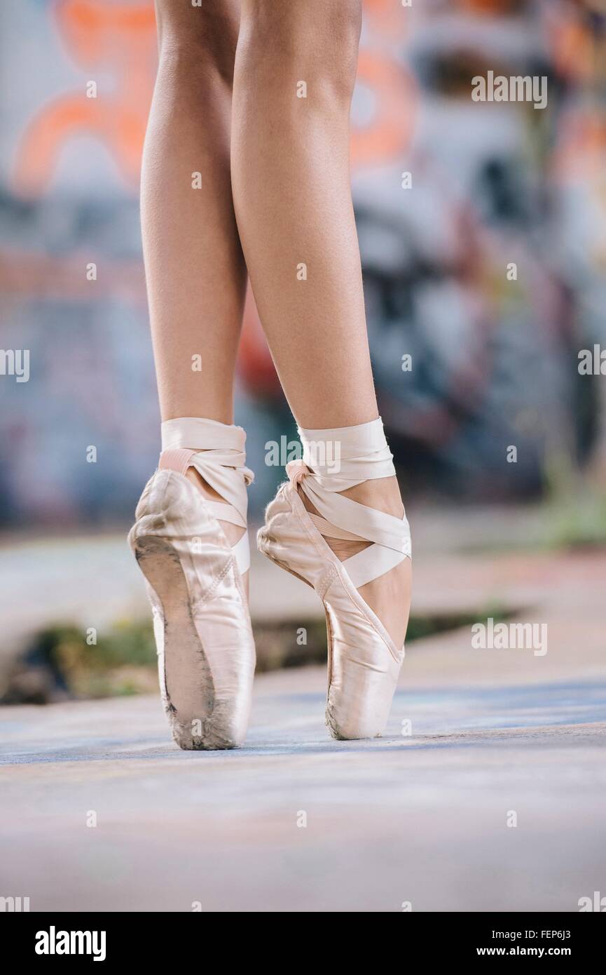 Jambes et Pieds de danseuse de ballet en pointe en face de graffitis Banque D'Images