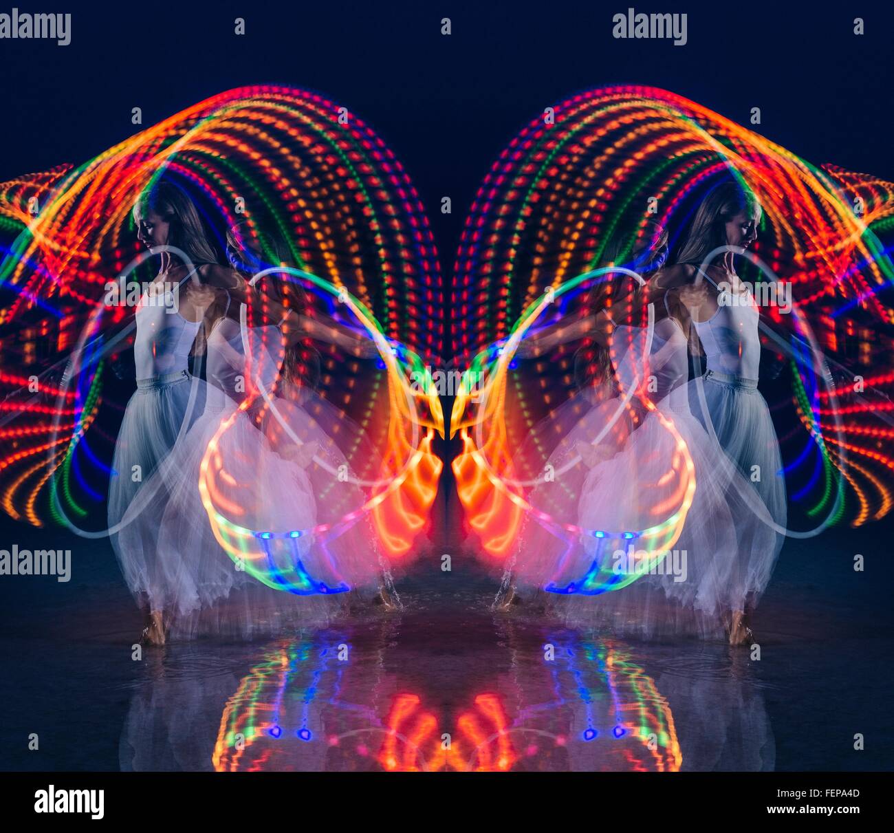 Composite symétrique de femme dansant avec multi-couleur lumineux hoop de nuit Banque D'Images