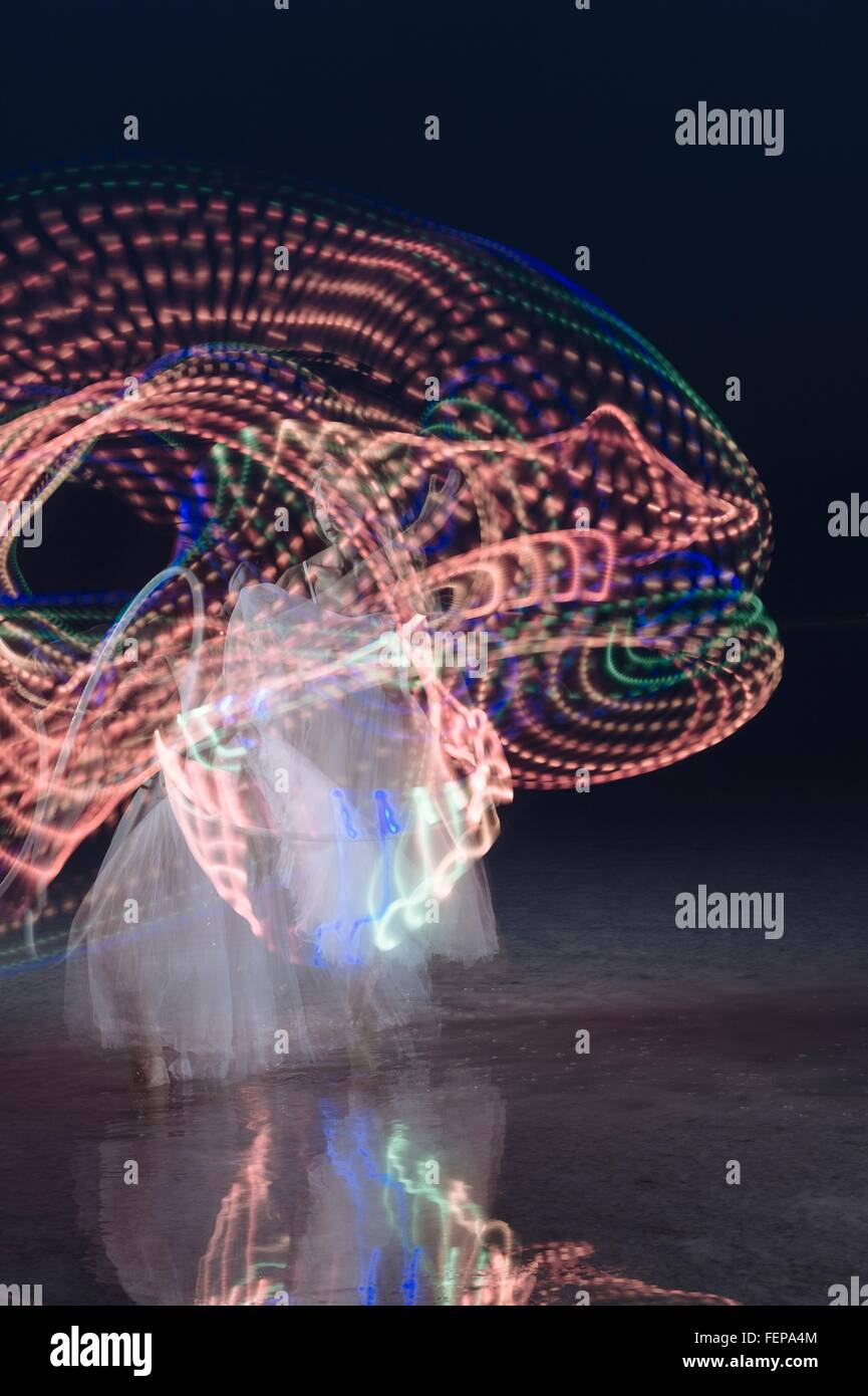 Femme dansant et multi-couleur lumineux tourbillonnant hoop de nuit Banque D'Images
