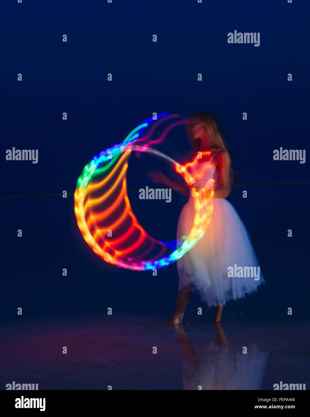 Woman wearing party dress prête avec multi-couleur lumineux hoop au crépuscule Banque D'Images